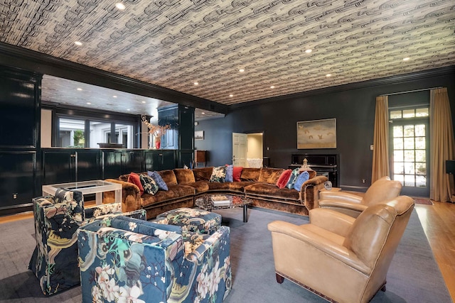 living room featuring crown molding, a stone fireplace, and hardwood / wood-style flooring