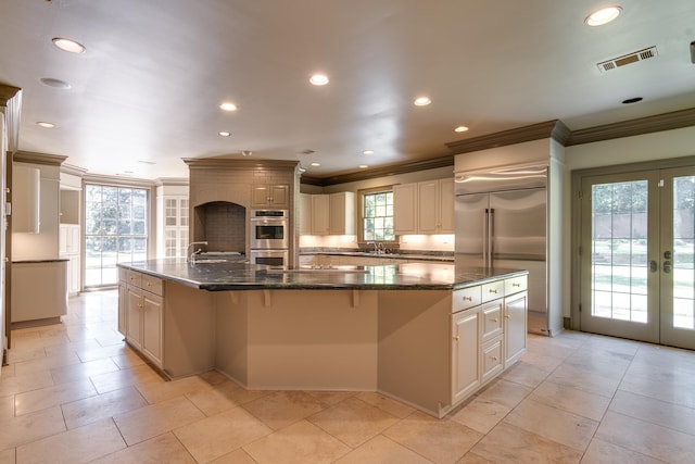 kitchen featuring a spacious island, appliances with stainless steel finishes, a healthy amount of sunlight, and dark stone countertops