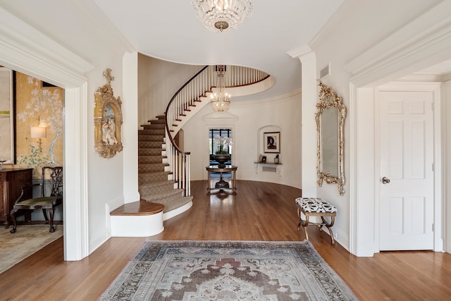 entrance foyer with an inviting chandelier, hardwood / wood-style flooring, and crown molding