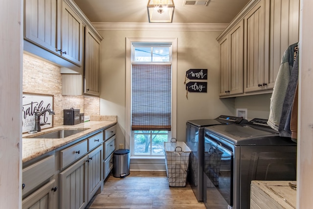 washroom with cabinets, a healthy amount of sunlight, crown molding, sink, and washer and clothes dryer