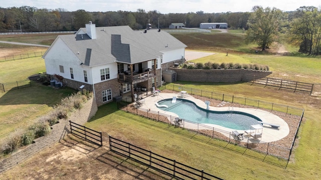 view of swimming pool featuring a rural view, a patio area, and a lawn