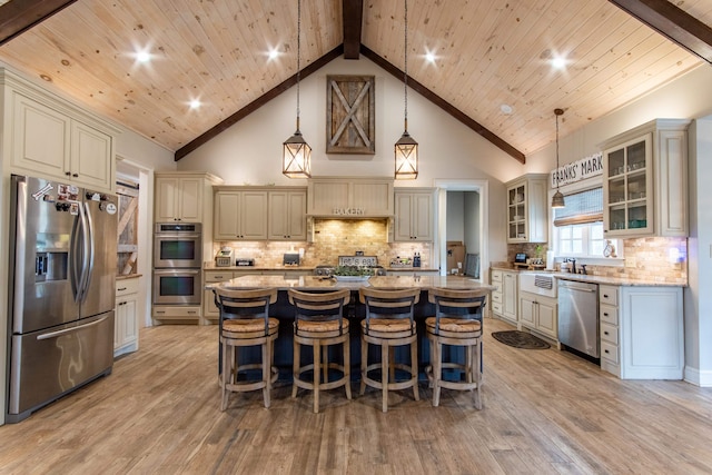 kitchen featuring a kitchen island, a kitchen breakfast bar, light wood-type flooring, stainless steel appliances, and decorative light fixtures