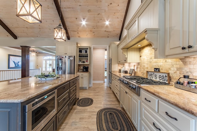 kitchen featuring a kitchen island, appliances with stainless steel finishes, decorative columns, pendant lighting, and light stone counters