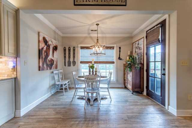 unfurnished dining area with ornamental molding, light hardwood / wood-style floors, a notable chandelier, and a healthy amount of sunlight