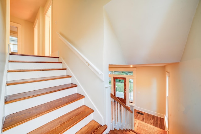 stairway with lofted ceiling and hardwood / wood-style flooring