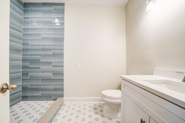 bathroom featuring vanity, tiled shower, toilet, and tile patterned flooring