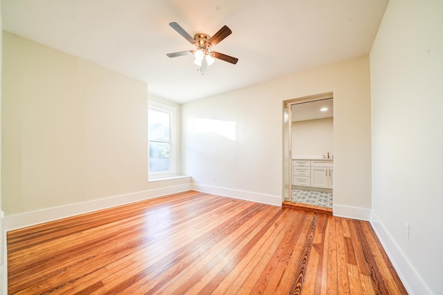 unfurnished bedroom with ensuite bath, light hardwood / wood-style floors, and ceiling fan