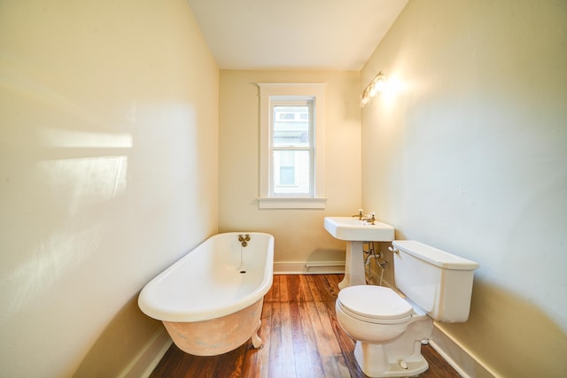 bathroom with toilet, hardwood / wood-style floors, and a bath