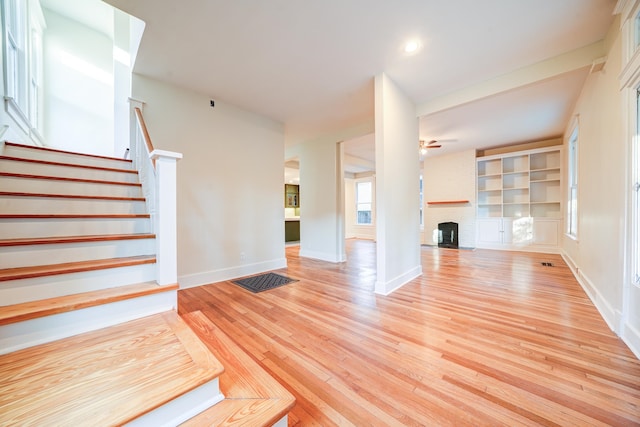 unfurnished living room featuring ceiling fan, light hardwood / wood-style flooring, and a fireplace