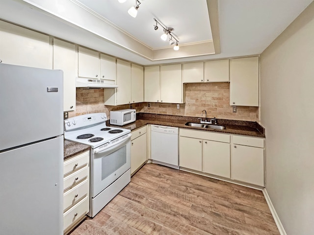 kitchen with tasteful backsplash, white appliances, sink, a tray ceiling, and light hardwood / wood-style flooring