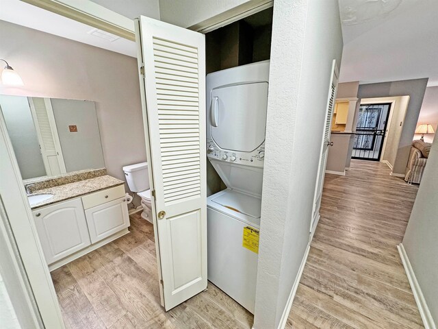 laundry area with stacked washer and dryer, sink, and light hardwood / wood-style floors