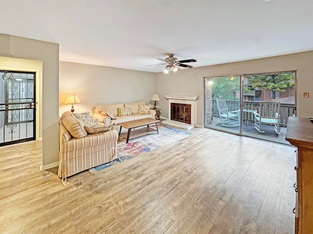 living room with a fireplace, light hardwood / wood-style flooring, and ceiling fan