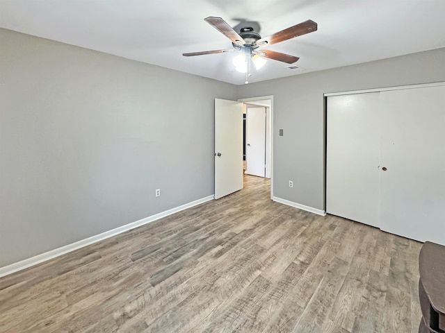 unfurnished bedroom with ceiling fan, a closet, and light wood-type flooring