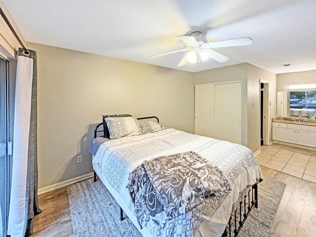 bedroom with ensuite bathroom, ceiling fan, a closet, and light wood-type flooring