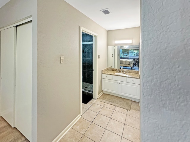 bathroom with walk in shower, tile patterned flooring, and vanity