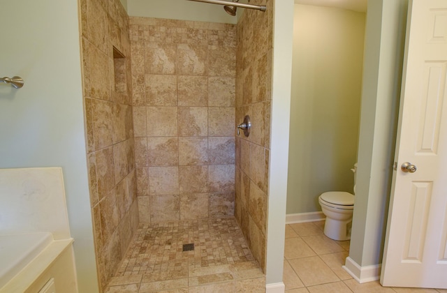 bathroom with tile patterned flooring, toilet, and tiled shower