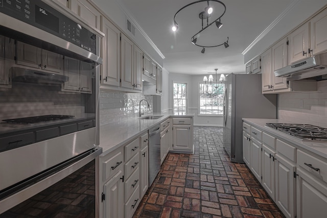 kitchen with appliances with stainless steel finishes, sink, white cabinetry, decorative backsplash, and a chandelier