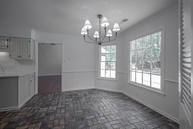 unfurnished dining area featuring ornamental molding and a notable chandelier