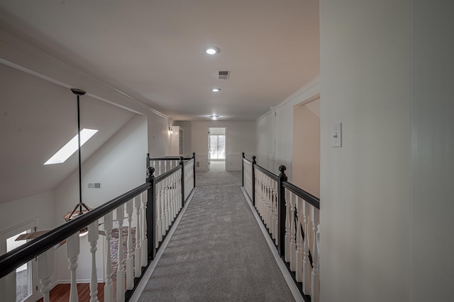 corridor featuring vaulted ceiling with skylight, crown molding, and carpet floors