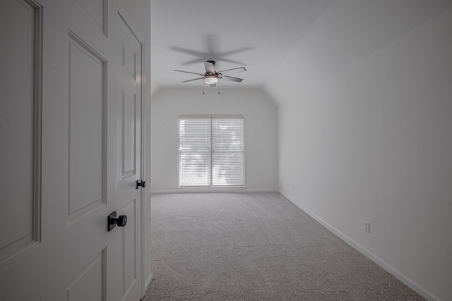 spare room with light carpet, vaulted ceiling, and ceiling fan