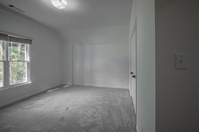 carpeted empty room featuring lofted ceiling