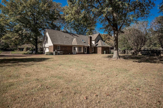 rear view of property with a yard, a garage, and central AC unit