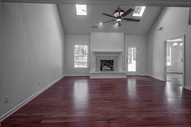 unfurnished living room with high vaulted ceiling, dark wood-type flooring, a skylight, and ceiling fan