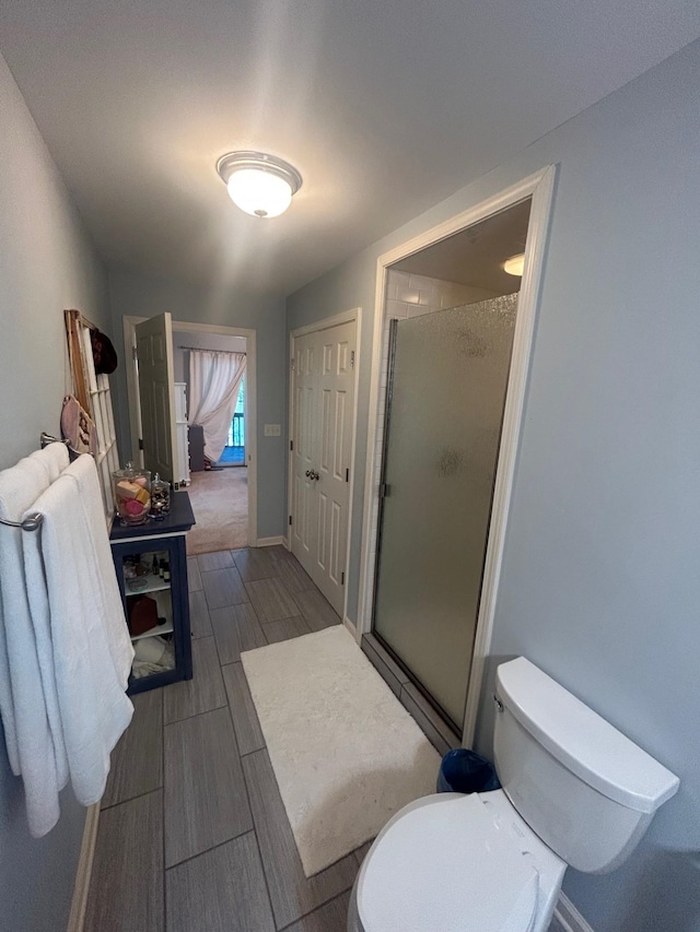 bathroom featuring a shower with door and toilet