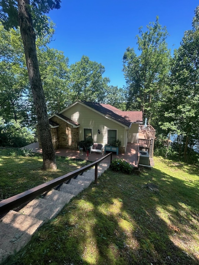 exterior space featuring a patio, a wooden deck, and a lawn