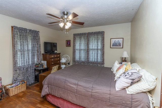 bedroom with a textured ceiling, wood-type flooring, and ceiling fan