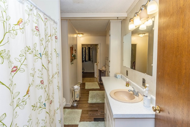 bathroom with vanity, hardwood / wood-style floors, ornamental molding, and toilet