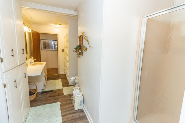 bathroom featuring a shower with door, wood-type flooring, toilet, vanity, and crown molding