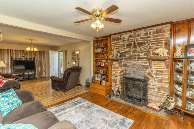 living room with a textured ceiling, a fireplace, wood-type flooring, and ceiling fan with notable chandelier