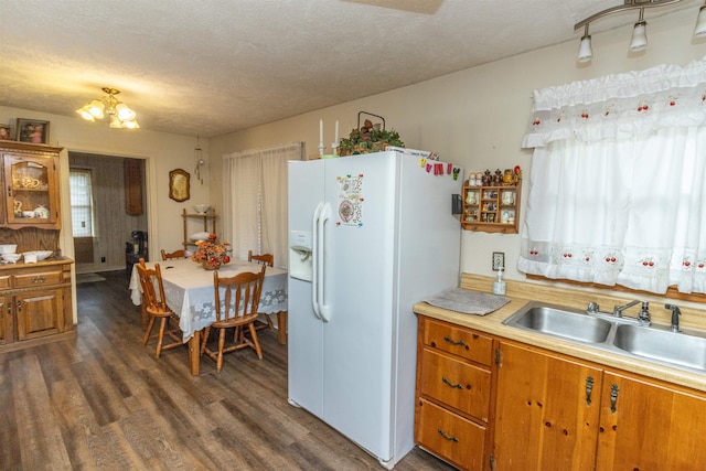 kitchen featuring dark hardwood / wood-style floors, white fridge with ice dispenser, sink, a notable chandelier, and a textured ceiling