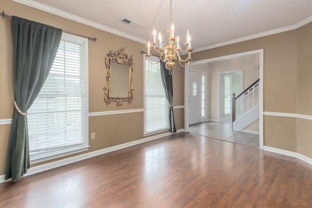 empty room with hardwood / wood-style flooring, a textured ceiling, and ornamental molding