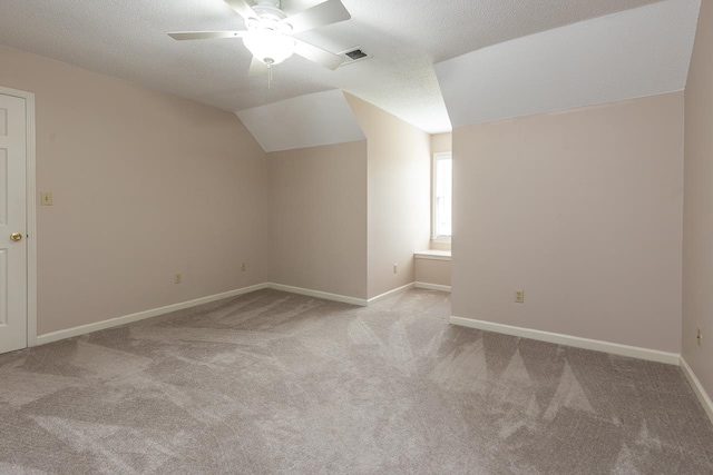 additional living space featuring lofted ceiling, light carpet, a textured ceiling, and ceiling fan