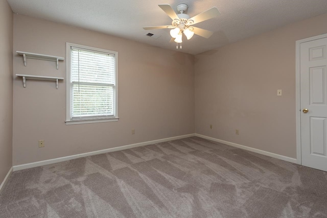 carpeted spare room featuring a textured ceiling and ceiling fan