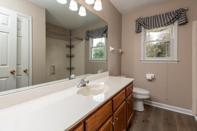 bathroom featuring toilet, hardwood / wood-style floors, vanity, a textured ceiling, and walk in shower