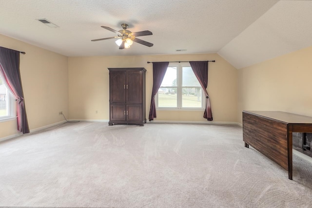 interior space featuring lofted ceiling, a textured ceiling, light colored carpet, and ceiling fan