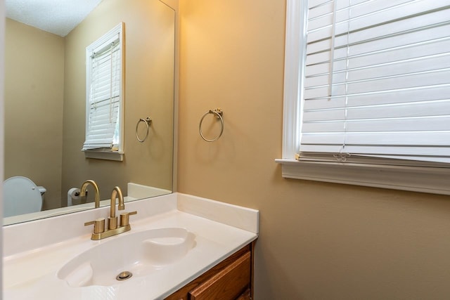 bathroom featuring vanity, a textured ceiling, and toilet