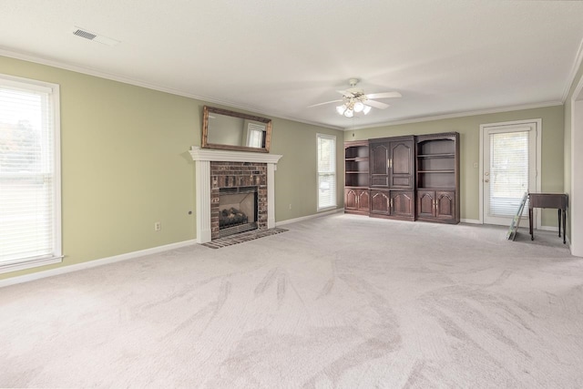 unfurnished living room with crown molding, a brick fireplace, light colored carpet, and ceiling fan