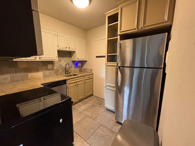 kitchen featuring appliances with stainless steel finishes, sink, a textured ceiling, light stone counters, and decorative backsplash