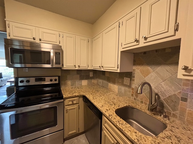 kitchen featuring decorative backsplash, stainless steel appliances, sink, white cabinets, and light stone counters