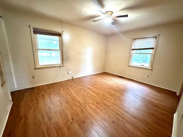 empty room with hardwood / wood-style floors and ceiling fan