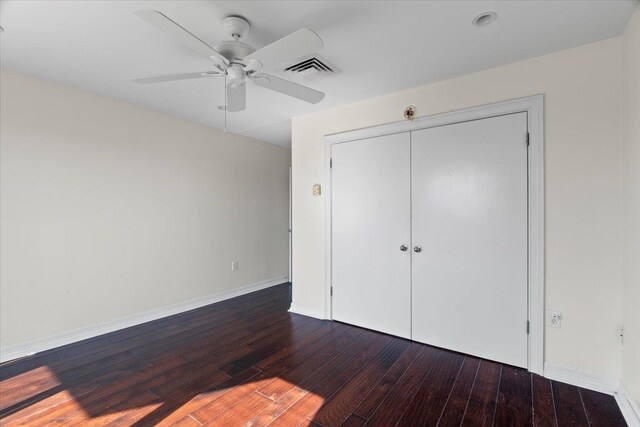 unfurnished bedroom with a closet, dark hardwood / wood-style floors, and ceiling fan