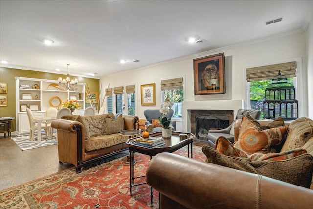 living room featuring hardwood / wood-style flooring, ornamental molding, a wealth of natural light, and a chandelier