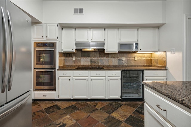 kitchen with appliances with stainless steel finishes, white cabinets, dark stone countertops, and wine cooler