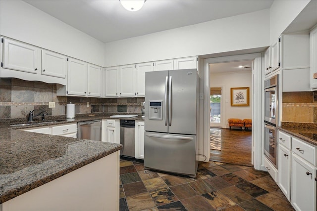 kitchen with decorative backsplash, white cabinetry, dark stone countertops, sink, and stainless steel appliances