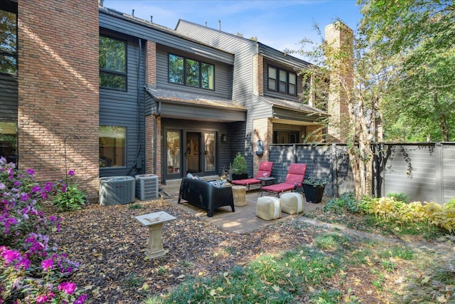 rear view of house featuring outdoor lounge area, cooling unit, and a patio