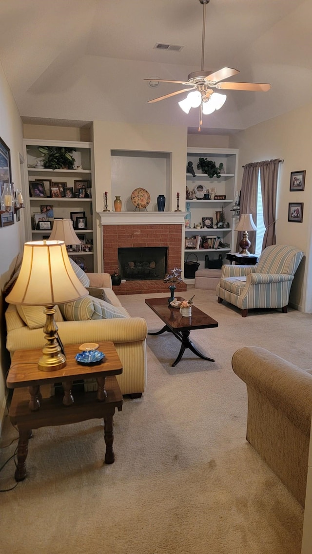 living room featuring built in shelves, a fireplace, carpet floors, and ceiling fan